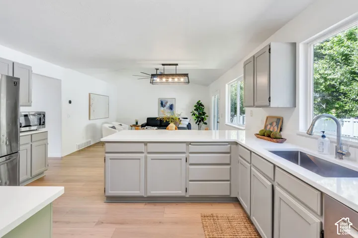 Kitchen featuring a large island with white countertops, light gray cabinetry, and wood-finish flooring
