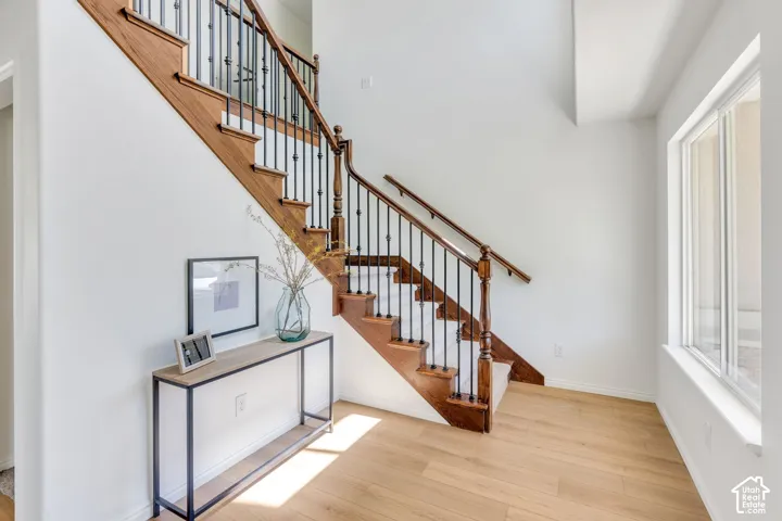 Grand staircase featuring dark wood newel posts, handrails, and balusters with wrought iron spindles