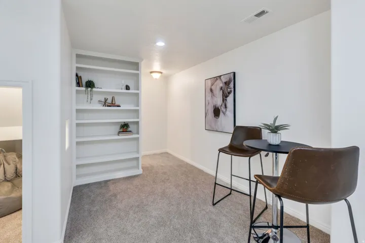 Built-in shelving unit with white finish and recessed lighting, complemented by light-toned carpet flooring and white walls