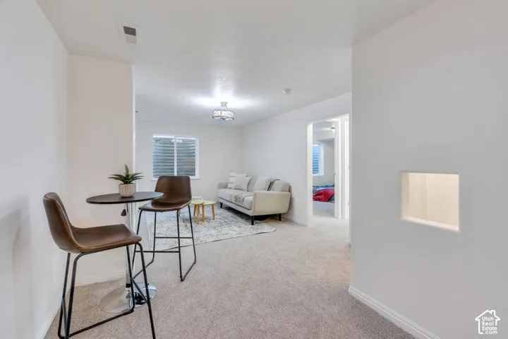 Carpeted living space featuring recessed lighting and a window with horizontal blinds