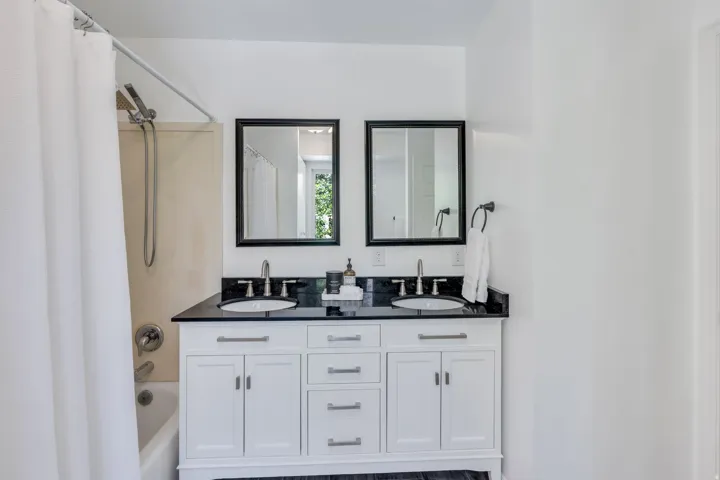 Bathroom featuring a dual vanity with white cabinetry, black countertops, and undermount sinks