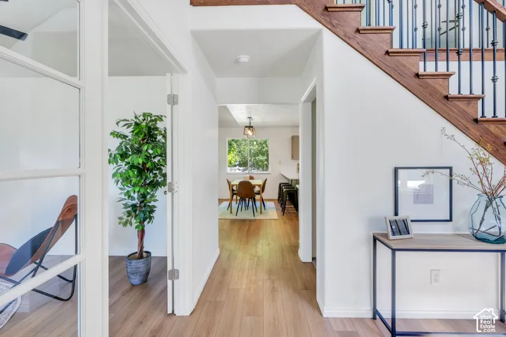 Hardwood staircase with wrought iron balusters, wood-finish flooring, and white wall finishes