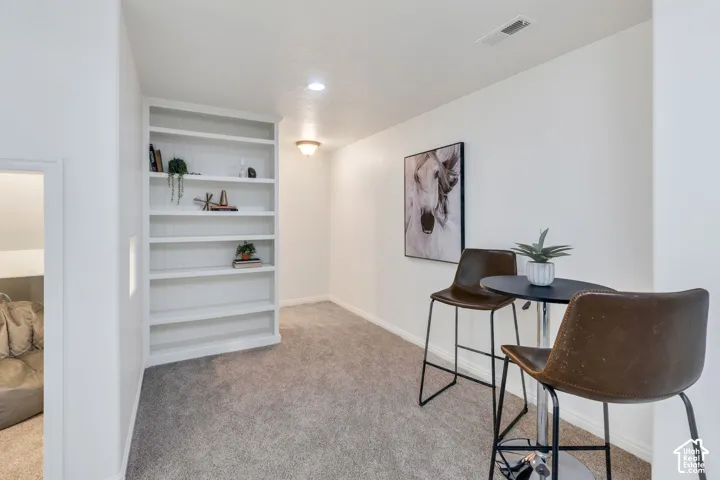 Built-in shelving unit with white finish and recessed lighting, complemented by light-toned carpet flooring and white walls