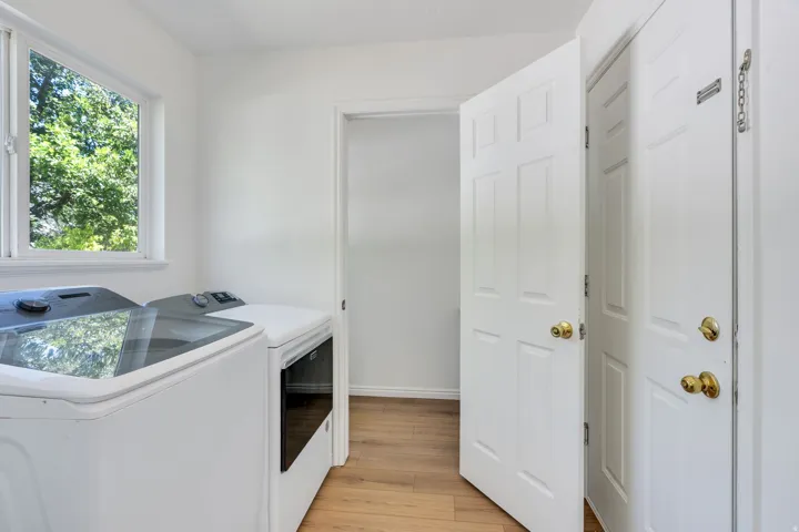 Laundry room featuring wood-finish flooring, a white window frame, and bright white walls