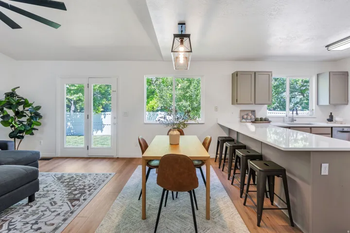 Open-concept living space featuring wood-finish flooring, white walls, and abundant natural light from multiple windows and glass-paneled French doors
