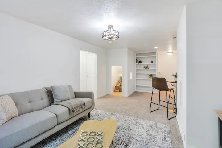 Spacious living area featuring neutral carpeting, white walls, and an ornate ceiling fixture