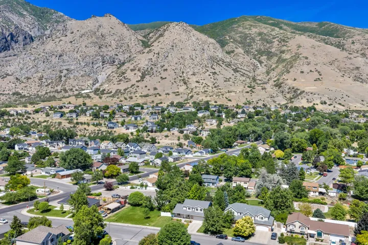 Aerial perspective showcasing a residential community nestled at the base of expansive, rugged mountains