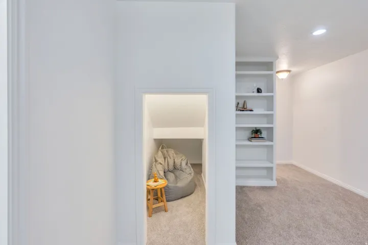 Built-in shelving unit with recessed lighting, complemented by a separate alcove with plush carpeting