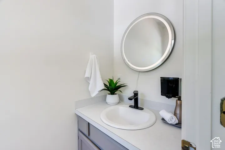 Bathroom vanity featuring a light-toned countertop, undermount sink, and matte black faucet