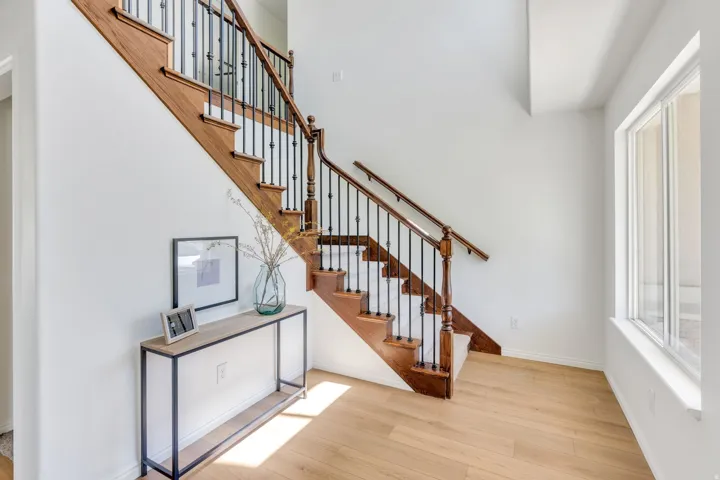 Grand staircase featuring dark wood newel posts, handrails, and balusters with wrought iron spindles