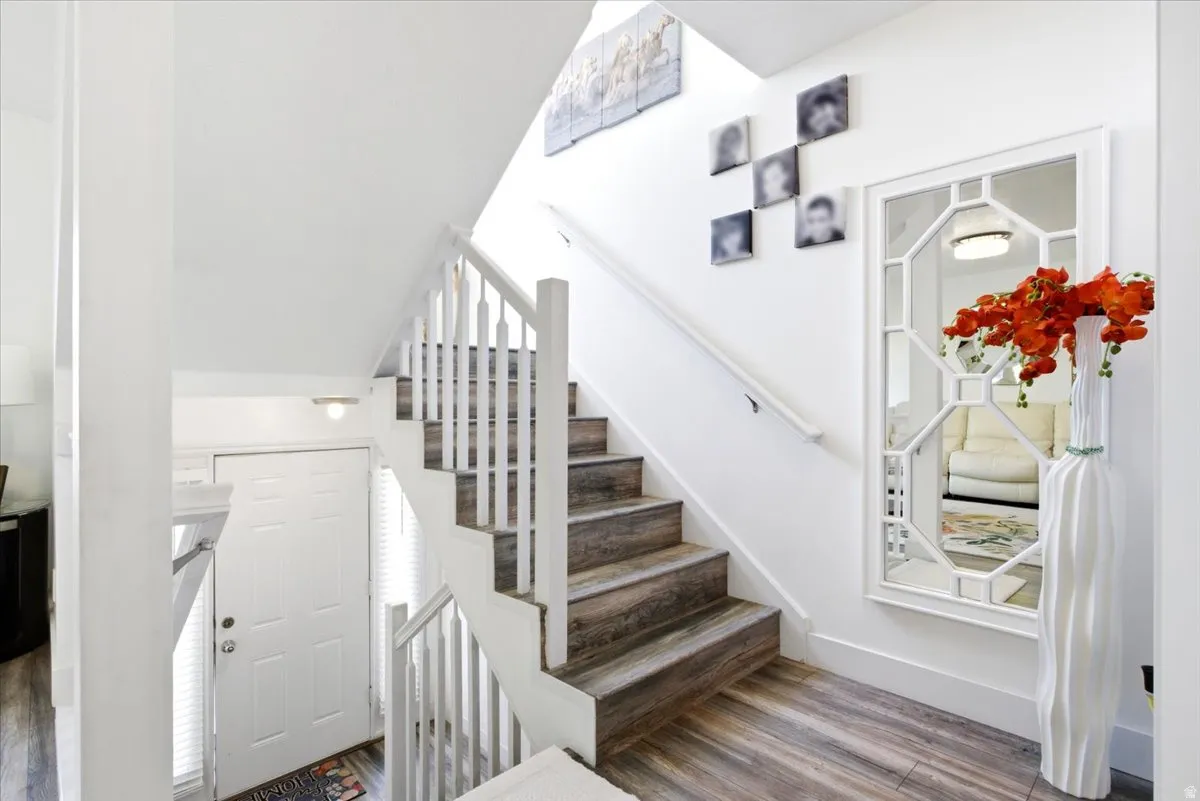 Entryway featuring a staircase with wood-finish treads and white balusters