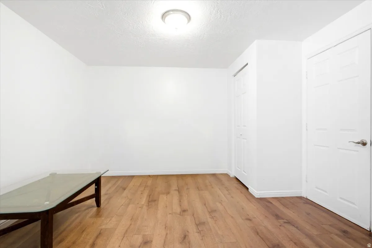 Spacious room featuring wood-finish flooring, white baseboards, and a flush mount ceiling light