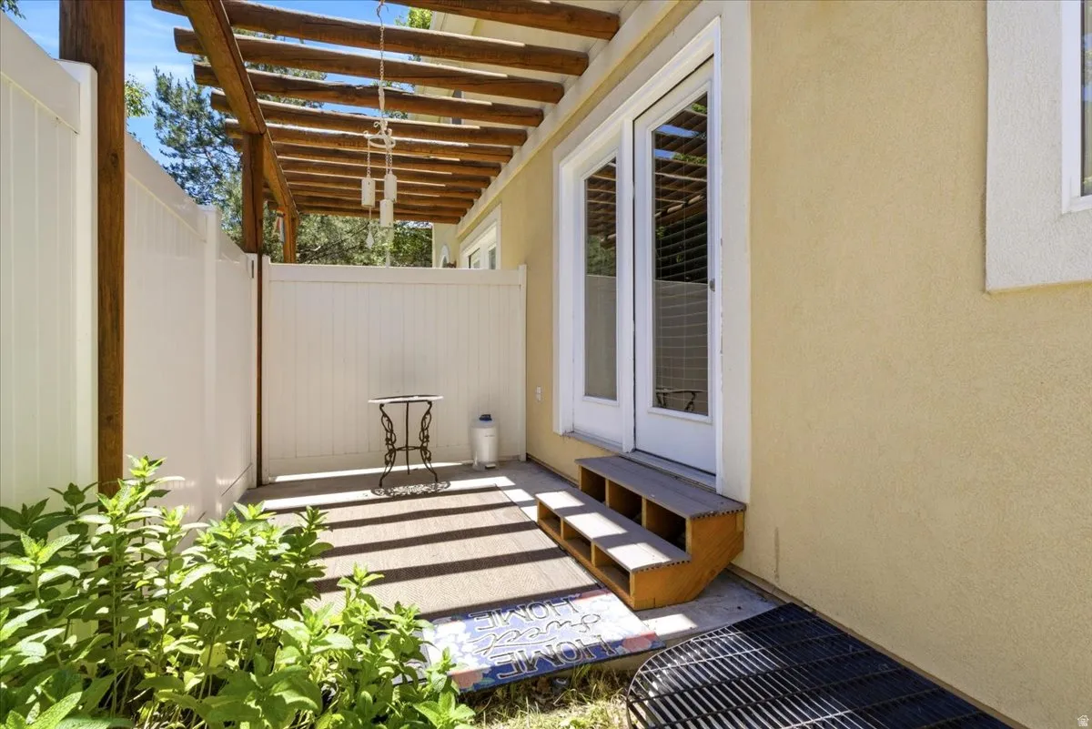 Private patio featuring a wood pergola and white vinyl fencing