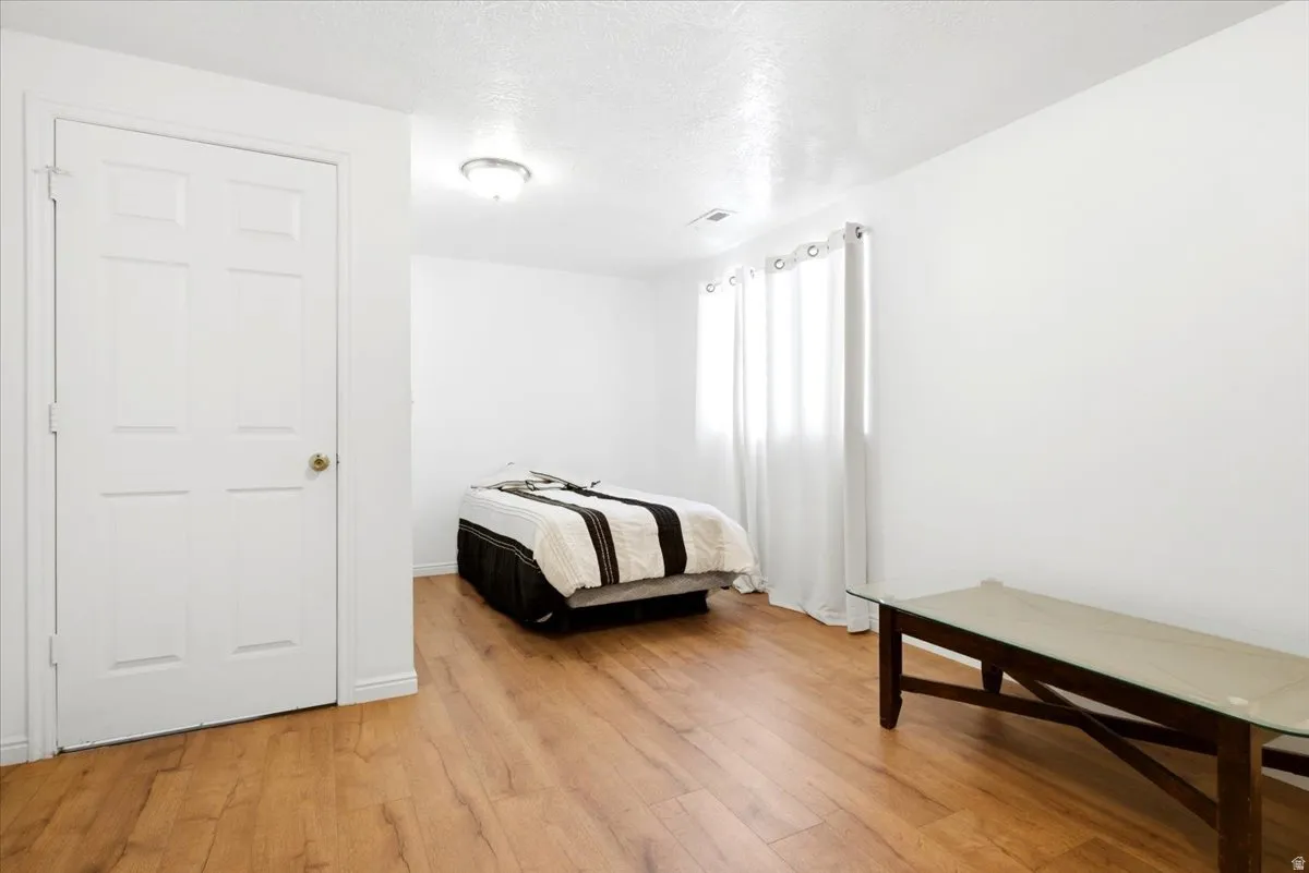 Bright room featuring wood-finish flooring, white walls, and a multi-paneled door