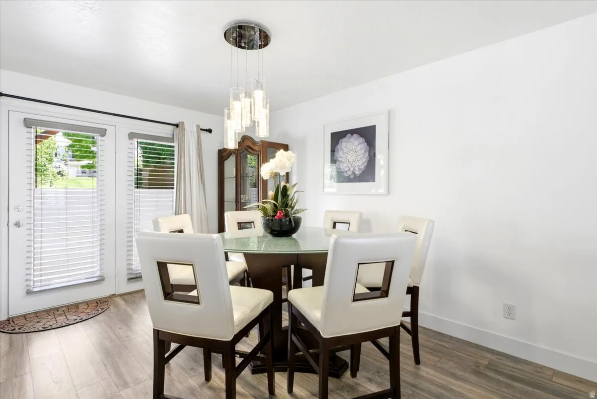 Bright room featuring wood-finish flooring, white walls, and a contemporary chandelier