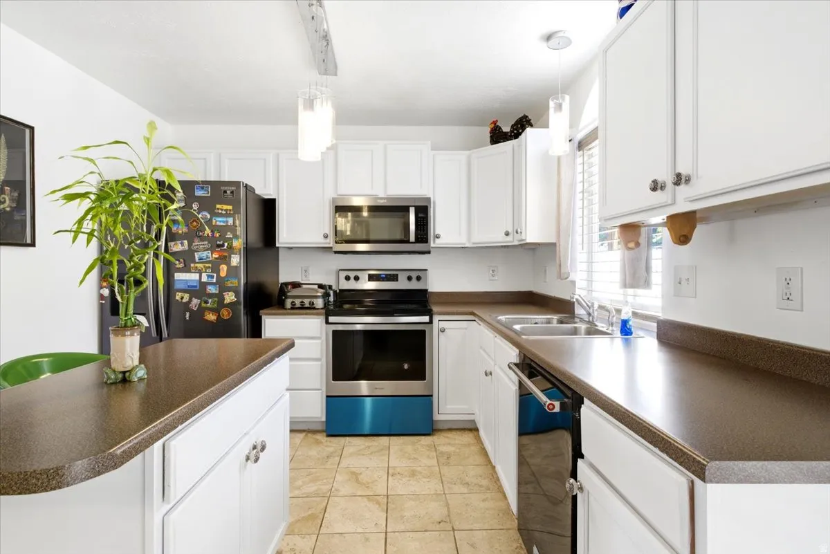 Kitchen featuring white cabinetry, dark countertops, stainless steel appliances, and tile flooring