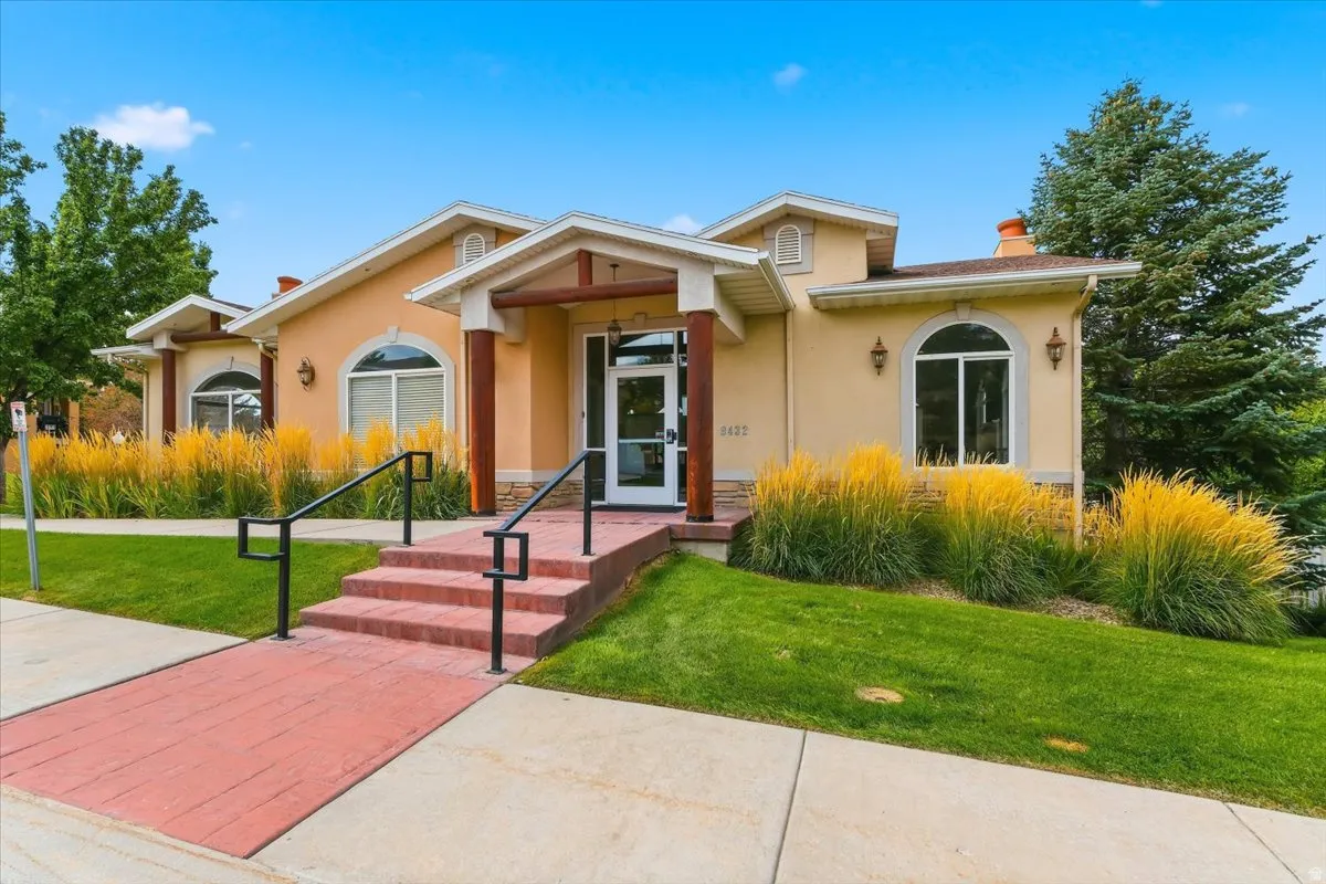 Stucco exterior with arched windows, brick steps, and mature landscaping