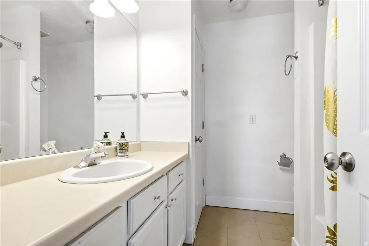 Bathroom vanity featuring an oval undermount sink, a chrome faucet, and white cabinetry with brushed nickel hardware