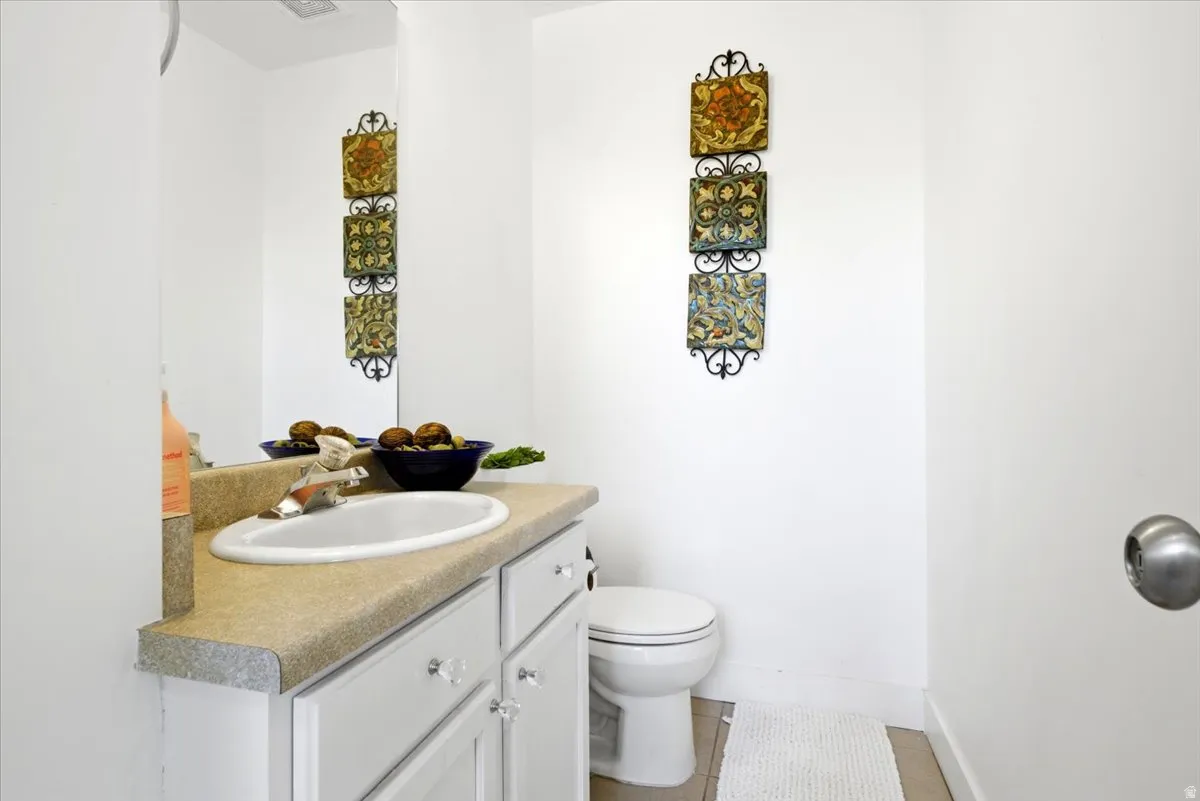 Bathroom featuring a vanity with an integrated sink, a light-toned countertop, and white cabinetry with clear knob hardware