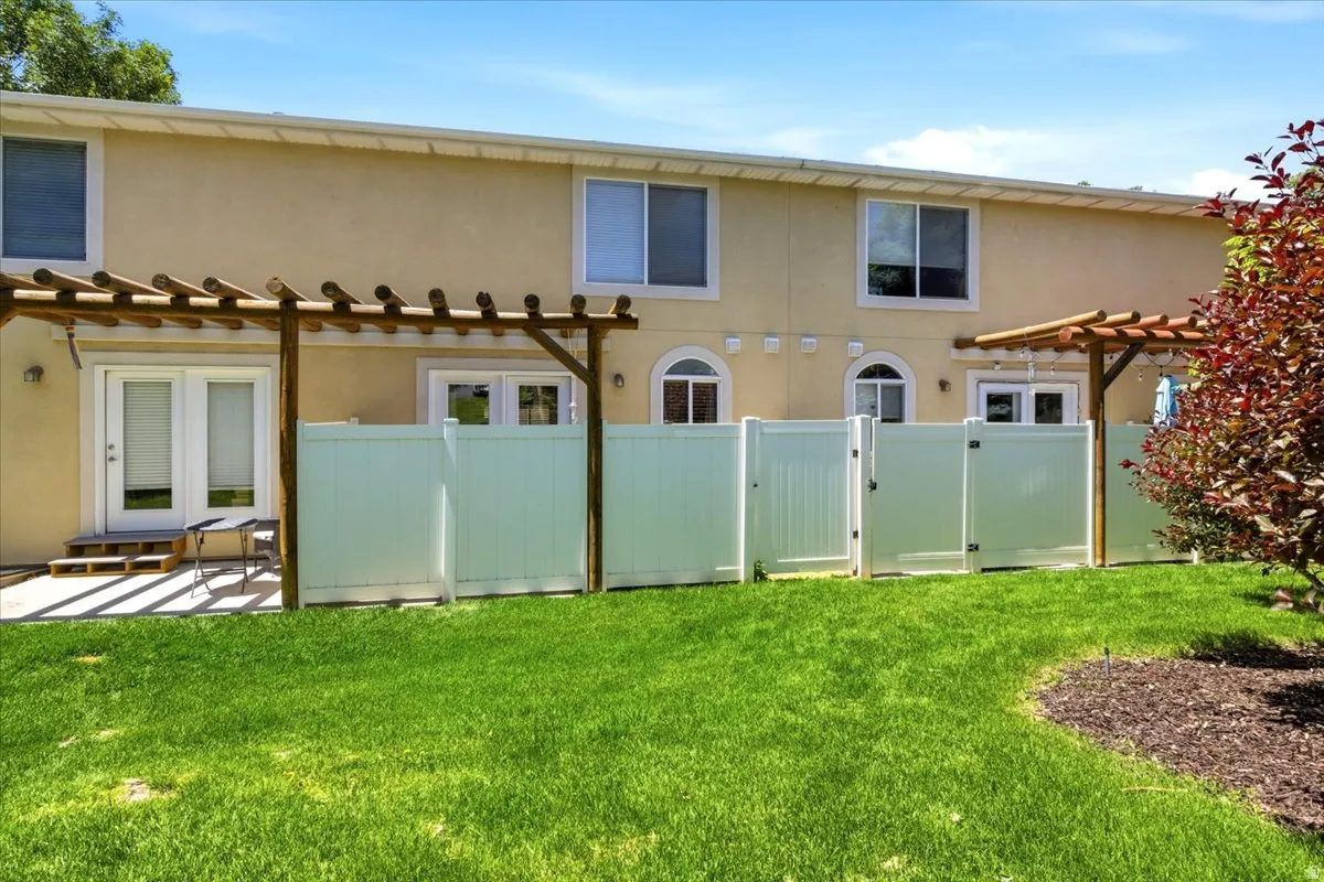 Expansive green lawn with a dedicated patio area featuring a wooden pergola