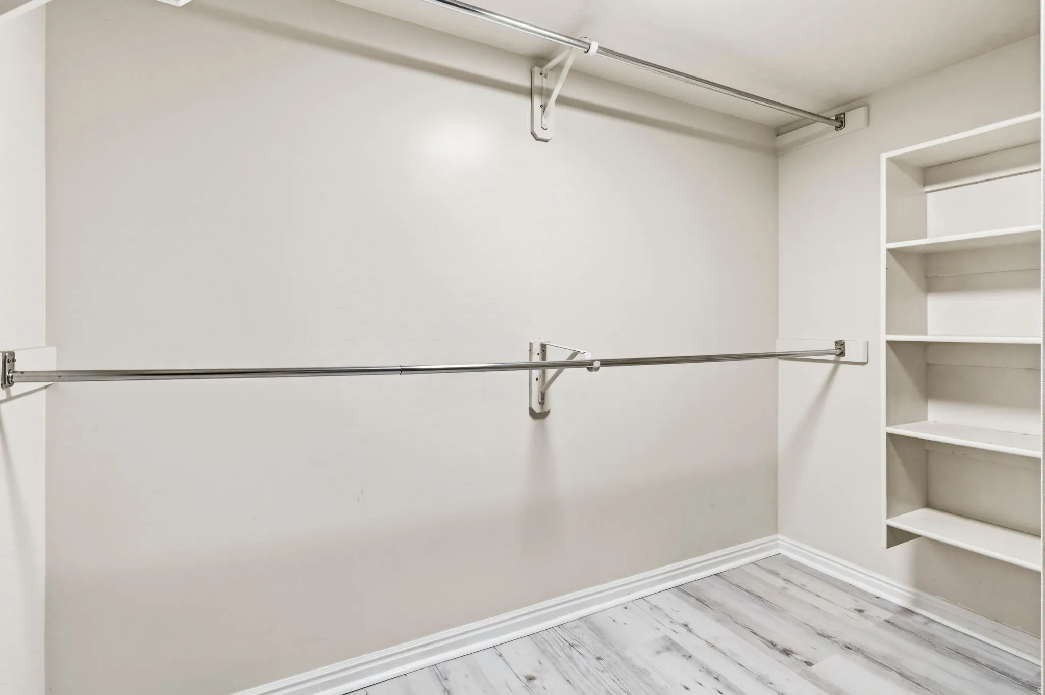 Chrome hanging rods, built-in shelving, and wood-finish flooring
