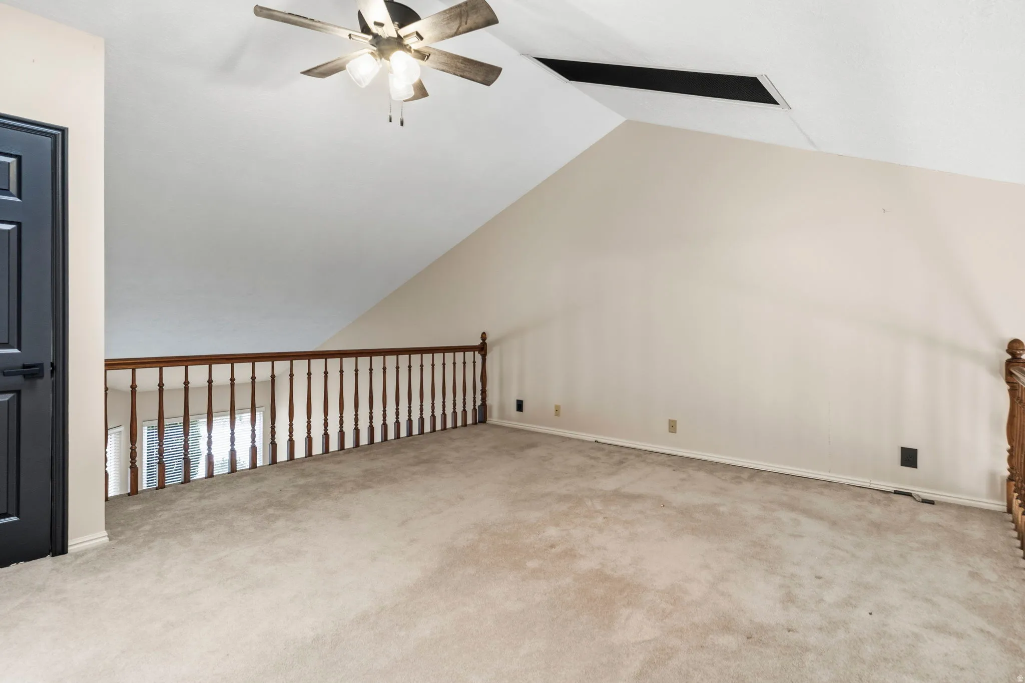 Loft area featuring vaulted ceiling, ceiling fan, and wood spindle railing
