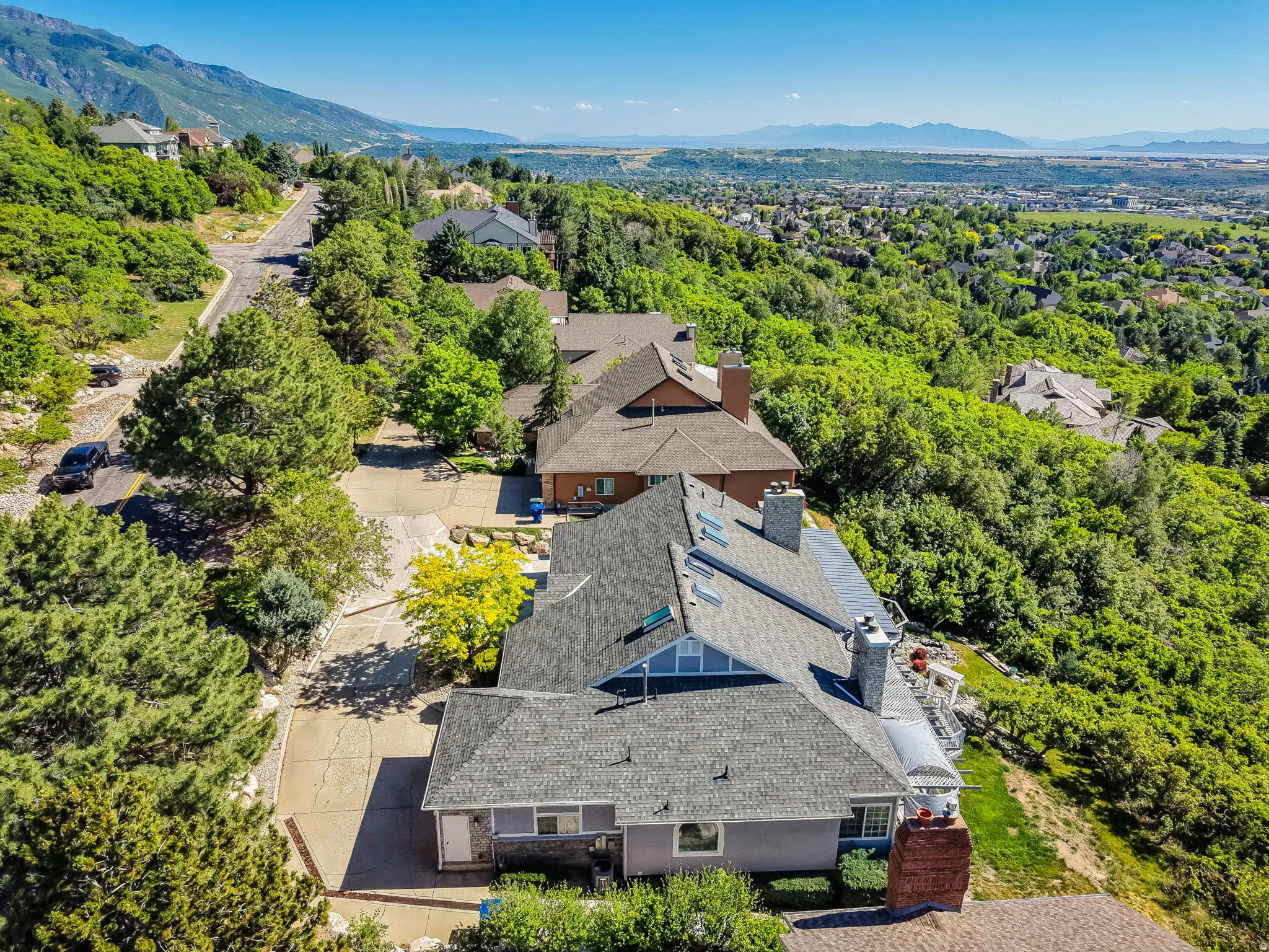 Property featuring a multi-level design with a gray shingled roof and brick chimneys
