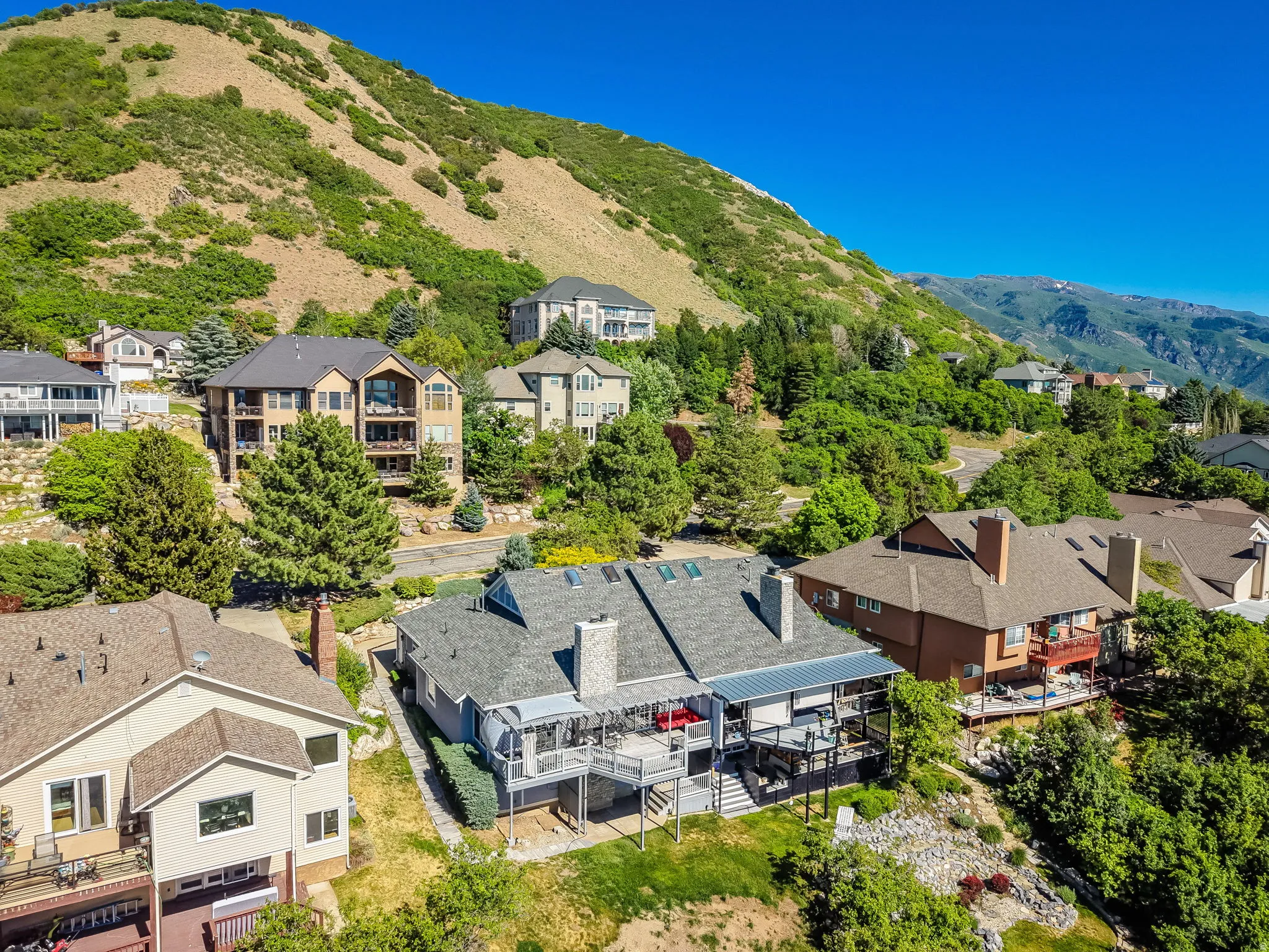 Hillside residence featuring a multi-level deck, covered patio, and mature landscaping