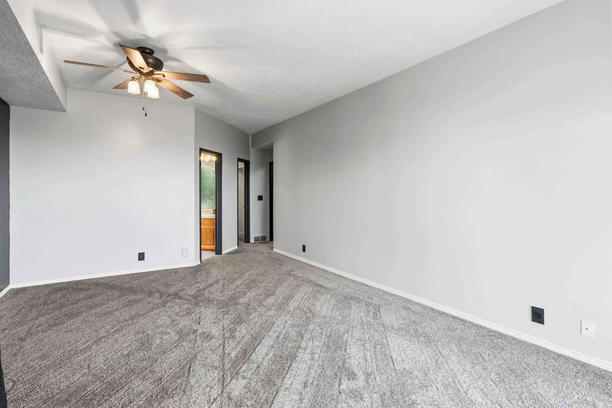 Neutral wall paint, ceiling fan with integrated lighting, and textured carpeting