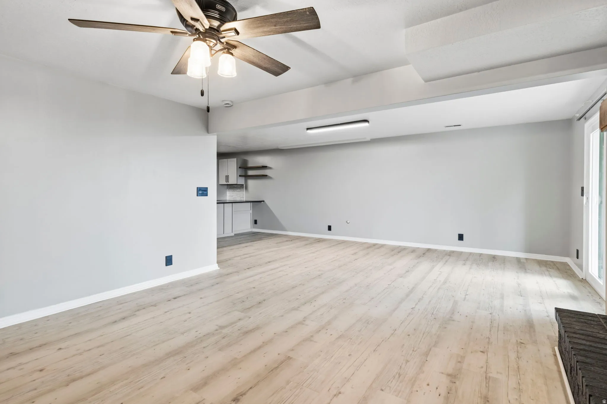 Wood-finish flooring, recessed lighting, ceiling fan, built-in shelving, sliding glass door