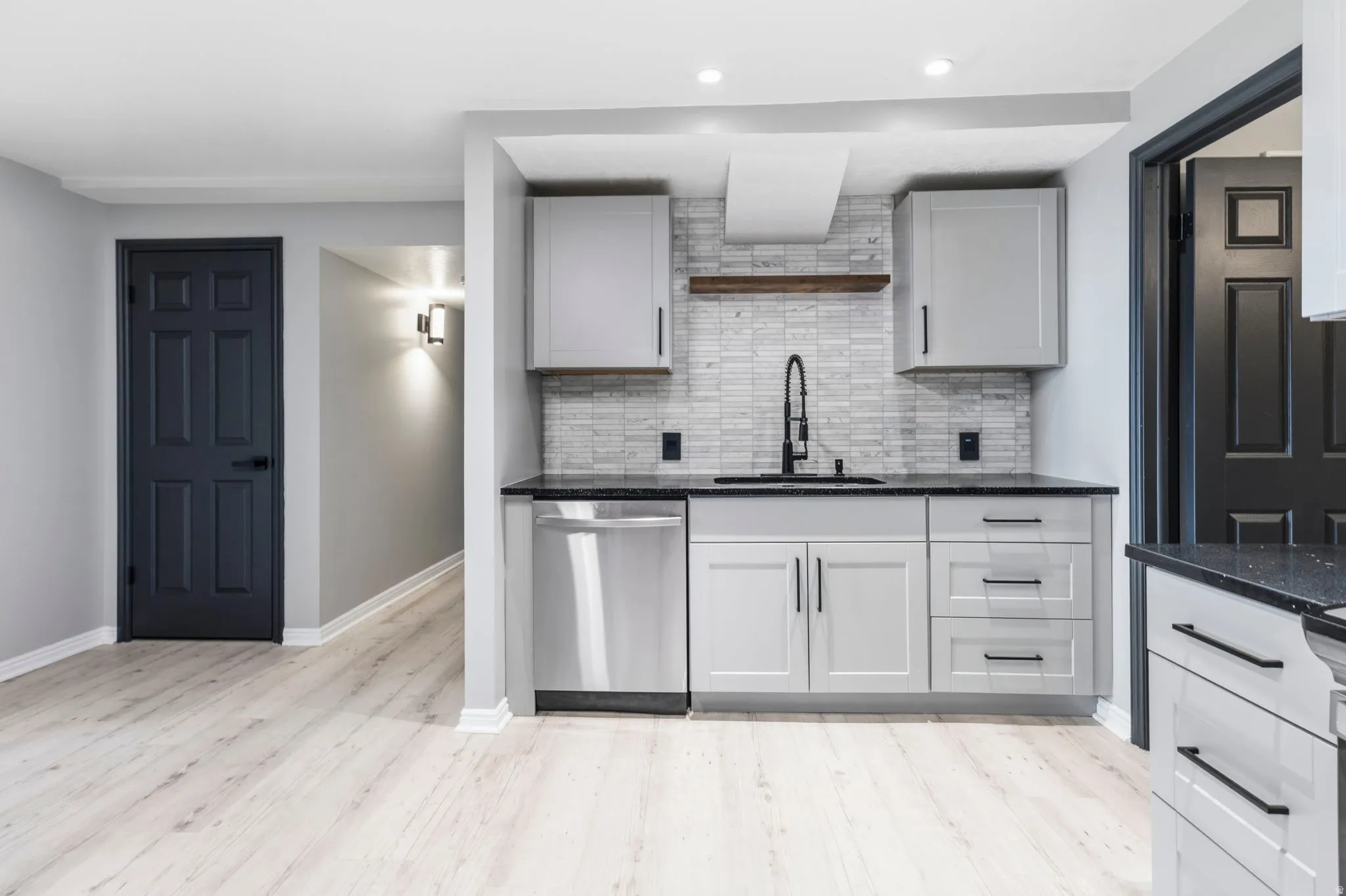 Kitchenette featuring light-toned cabinetry, dark countertops, and a tiled backsplash