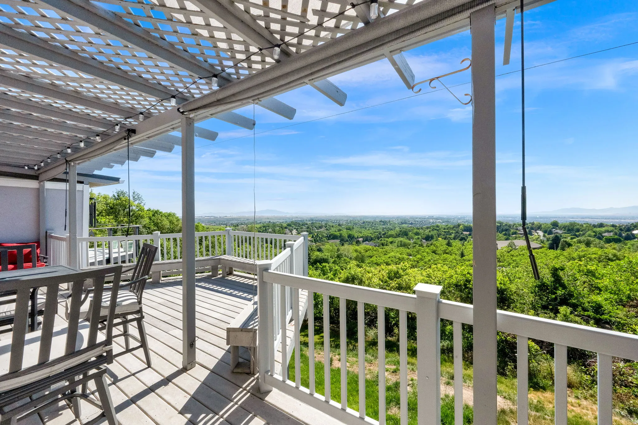 Expansive outdoor deck featuring a lattice pergola, white railing, and built-in bench seating