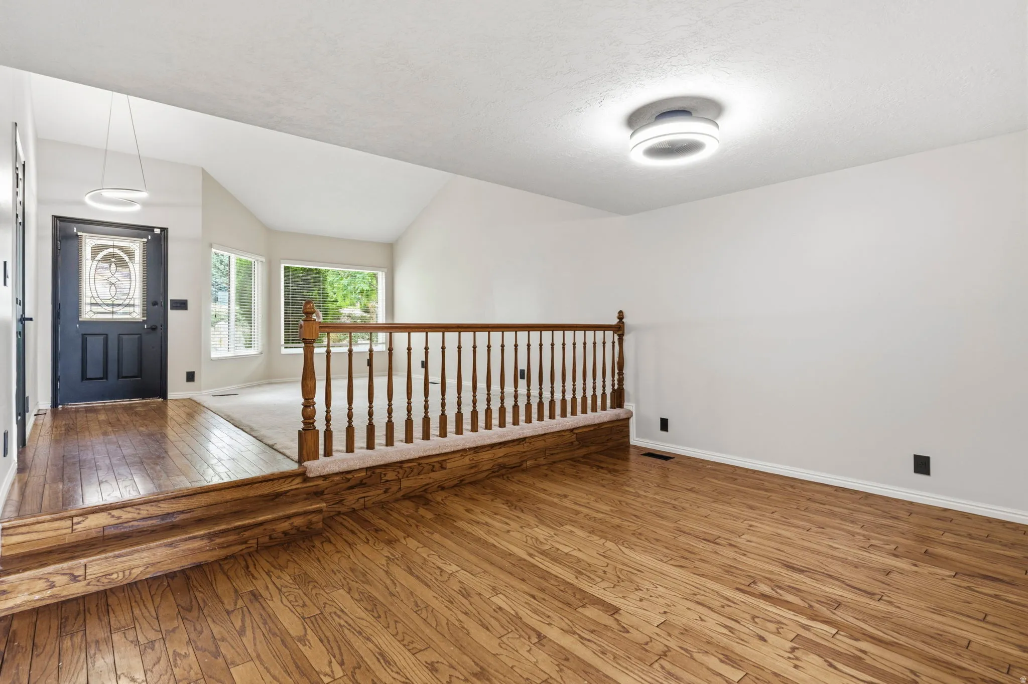 Wood-finish flooring throughout, with a decorative wood railing separating spaces