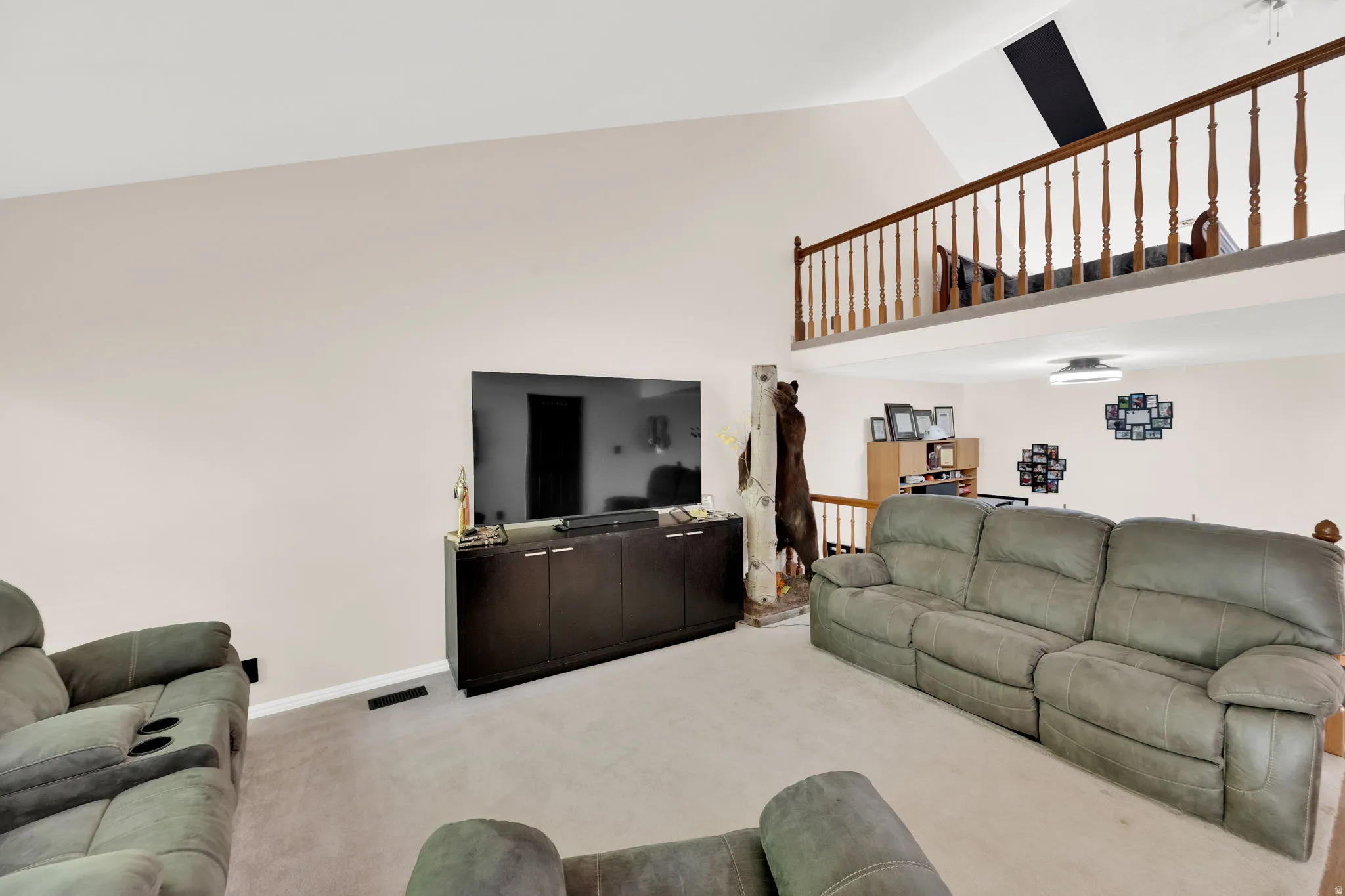 Living area with a vaulted ceiling and an open-concept upper level featuring a wood spindle railing