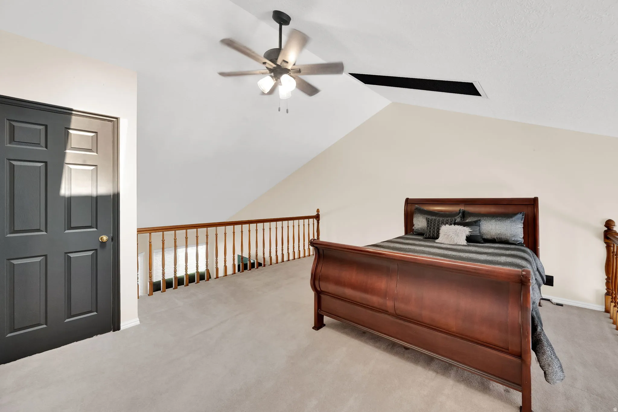 Carpeted loft space with a vaulted ceiling and a ceiling fan