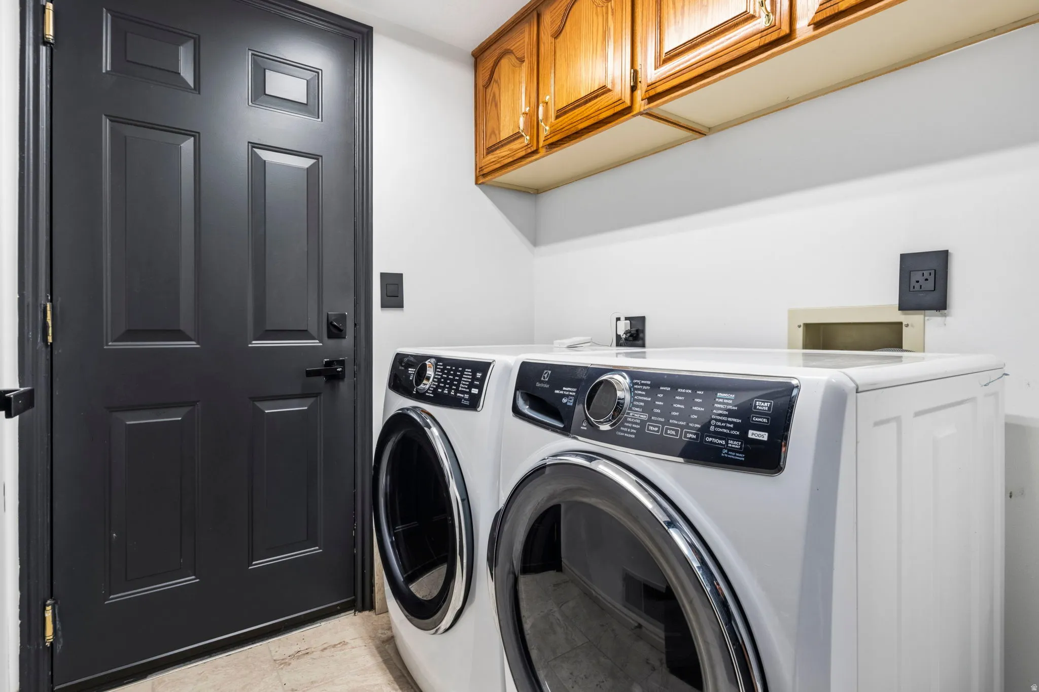 Laundry area featuring upper wood cabinetry and a paneled black door