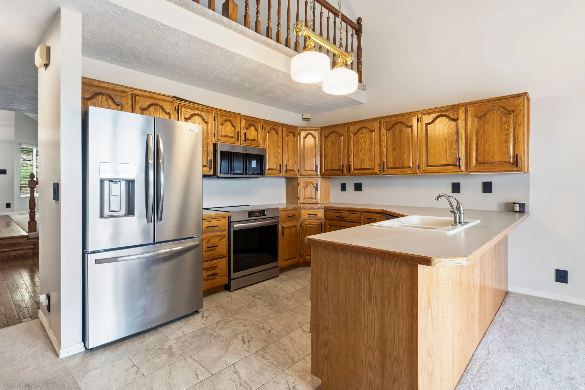 Kitchen featuring a stainless steel refrigerator, stainless steel oven, wood cabinetry, built-in sink, and kitchen island