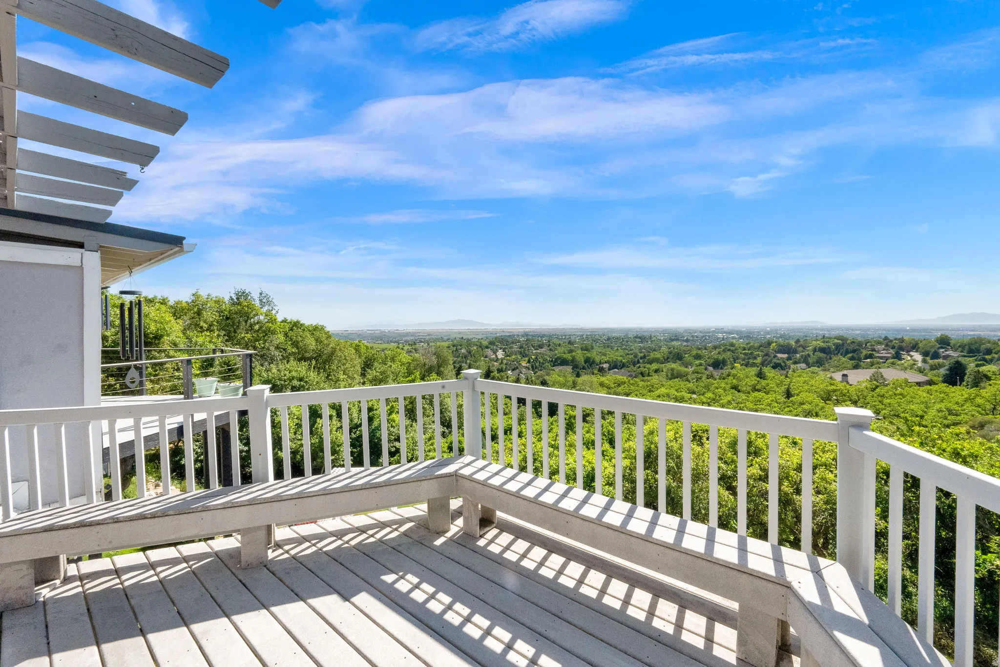 Expansive outdoor deck featuring wood-finish flooring, white railing, and built-in benches