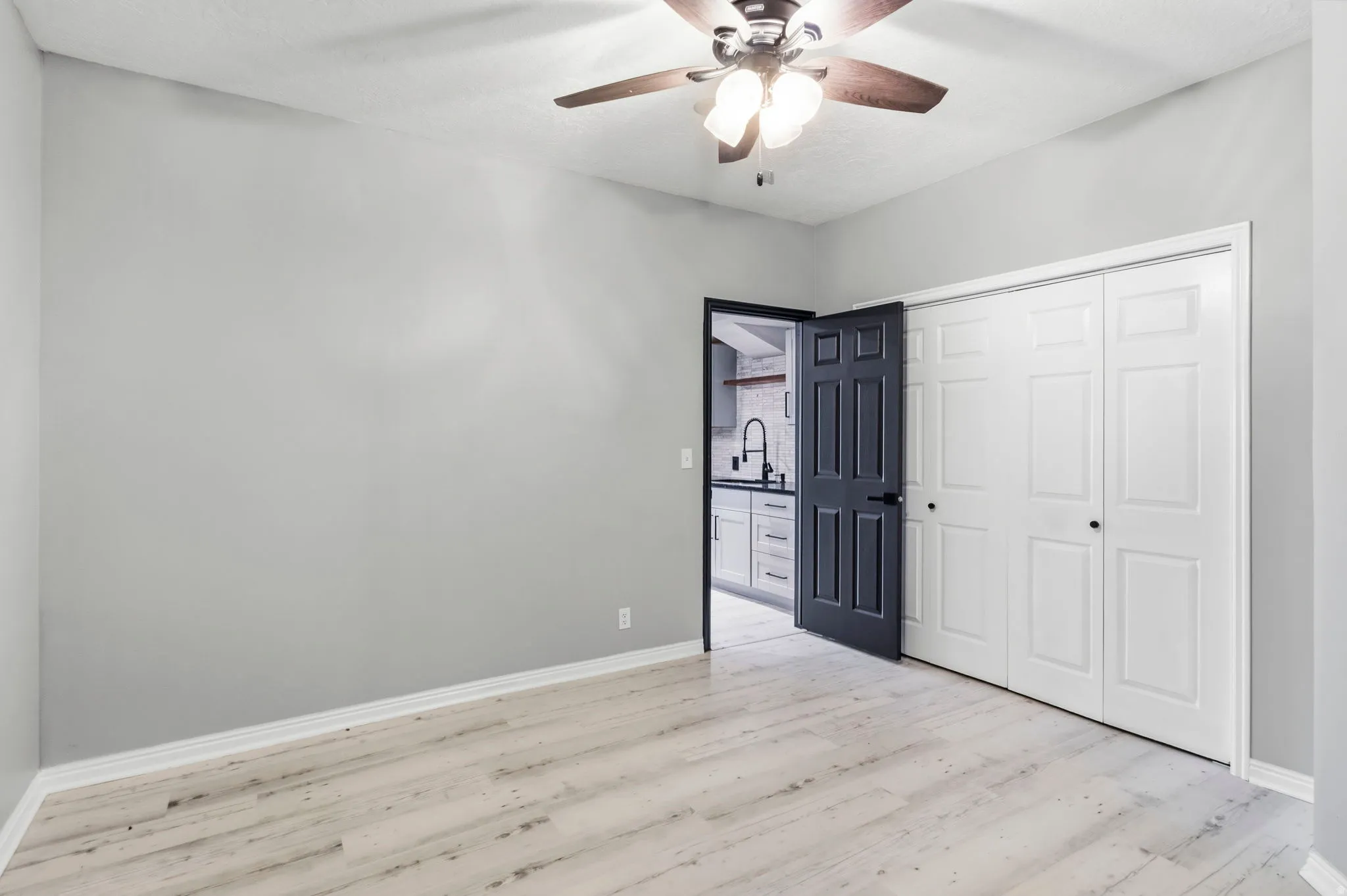 Wood-finish flooring, ceiling fan with integrated lighting, and bi-fold closet doors