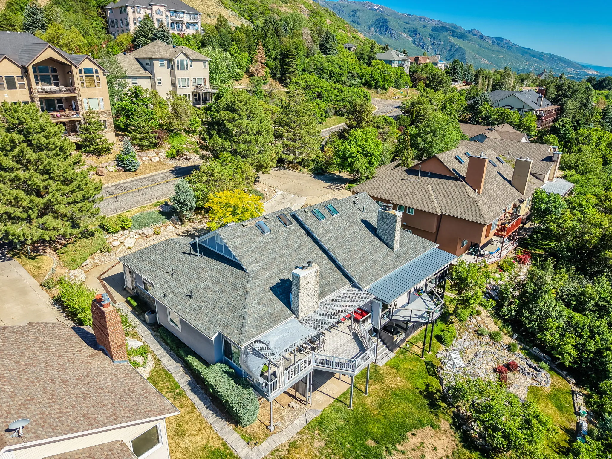 Spacious property featuring multiple expansive decks, a stone chimney, and a hillside setting
