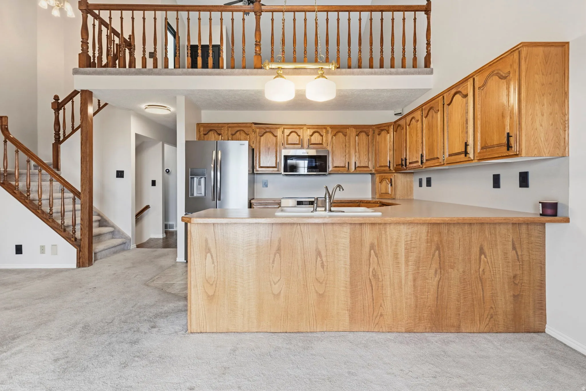Kitchen with wood-finish cabinetry, stainless steel appliances, and a built-in breakfast bar