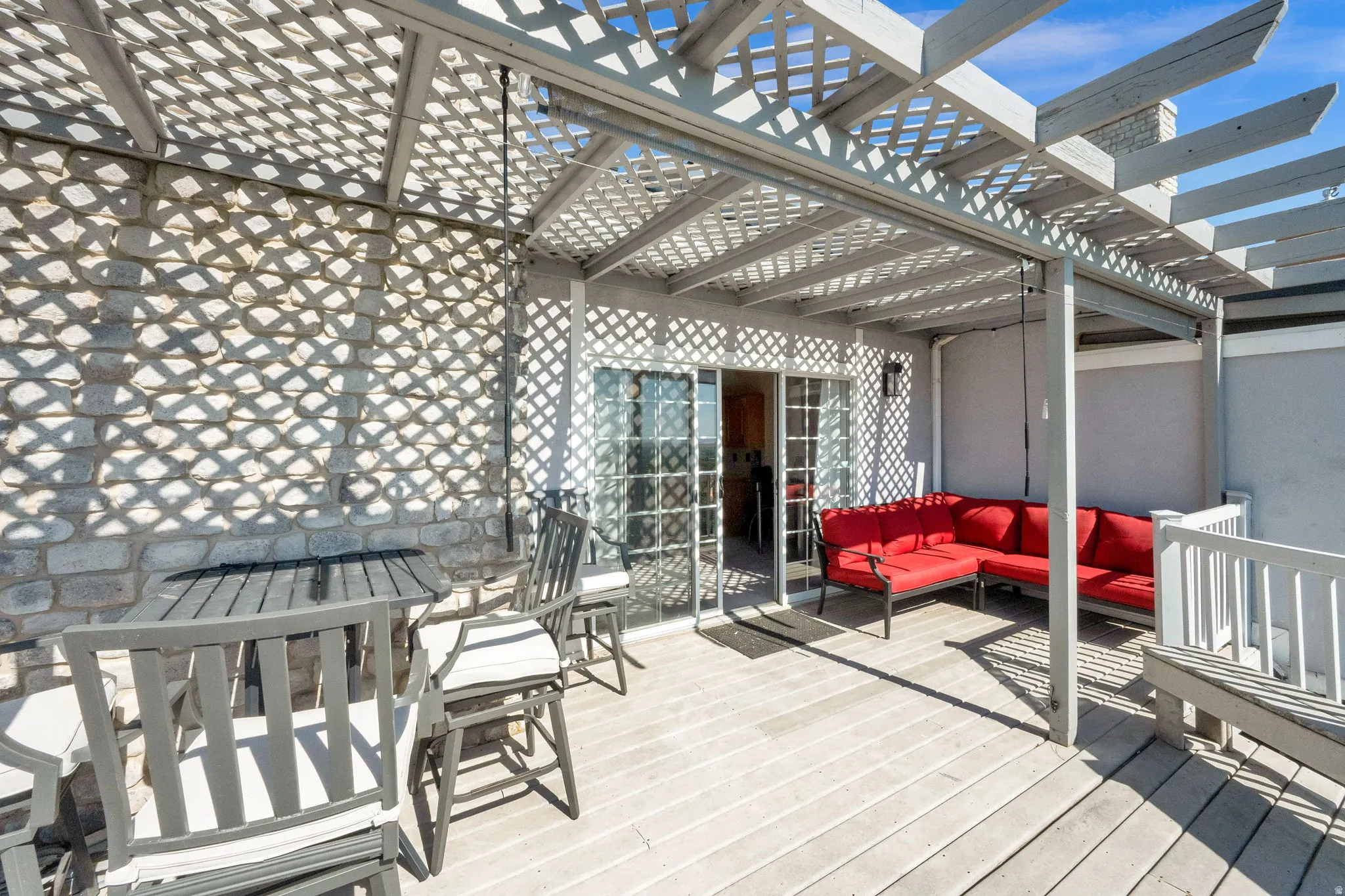 Rooftop deck featuring a slatted pergola, durable decking, stone wall, and sliding glass doors