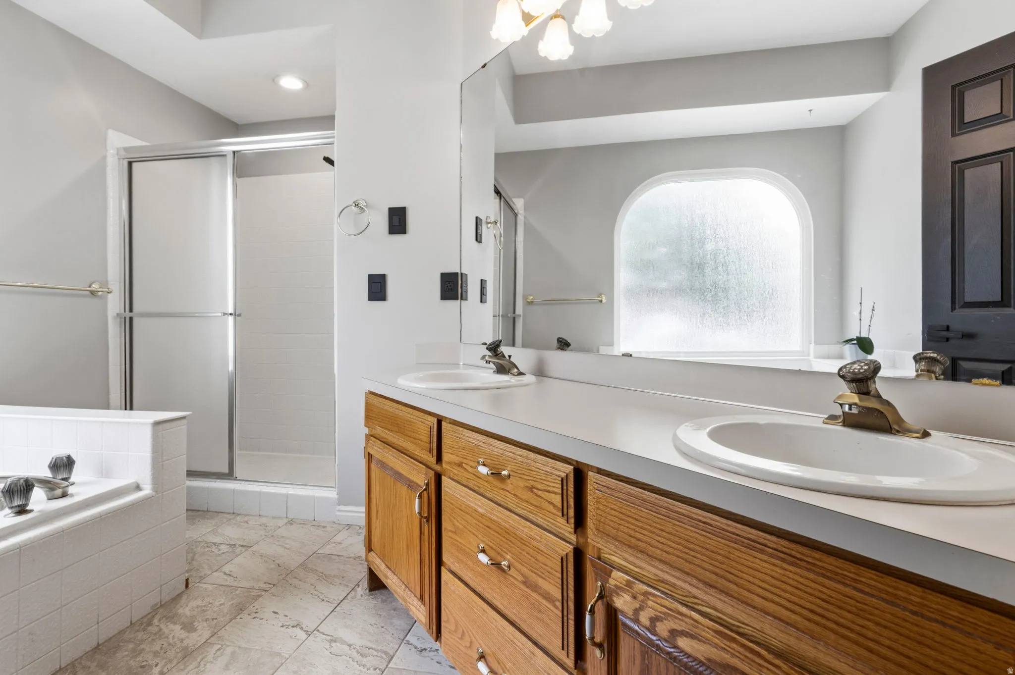 Dual vanity with wood-finish cabinetry, white countertops, and integrated sinks