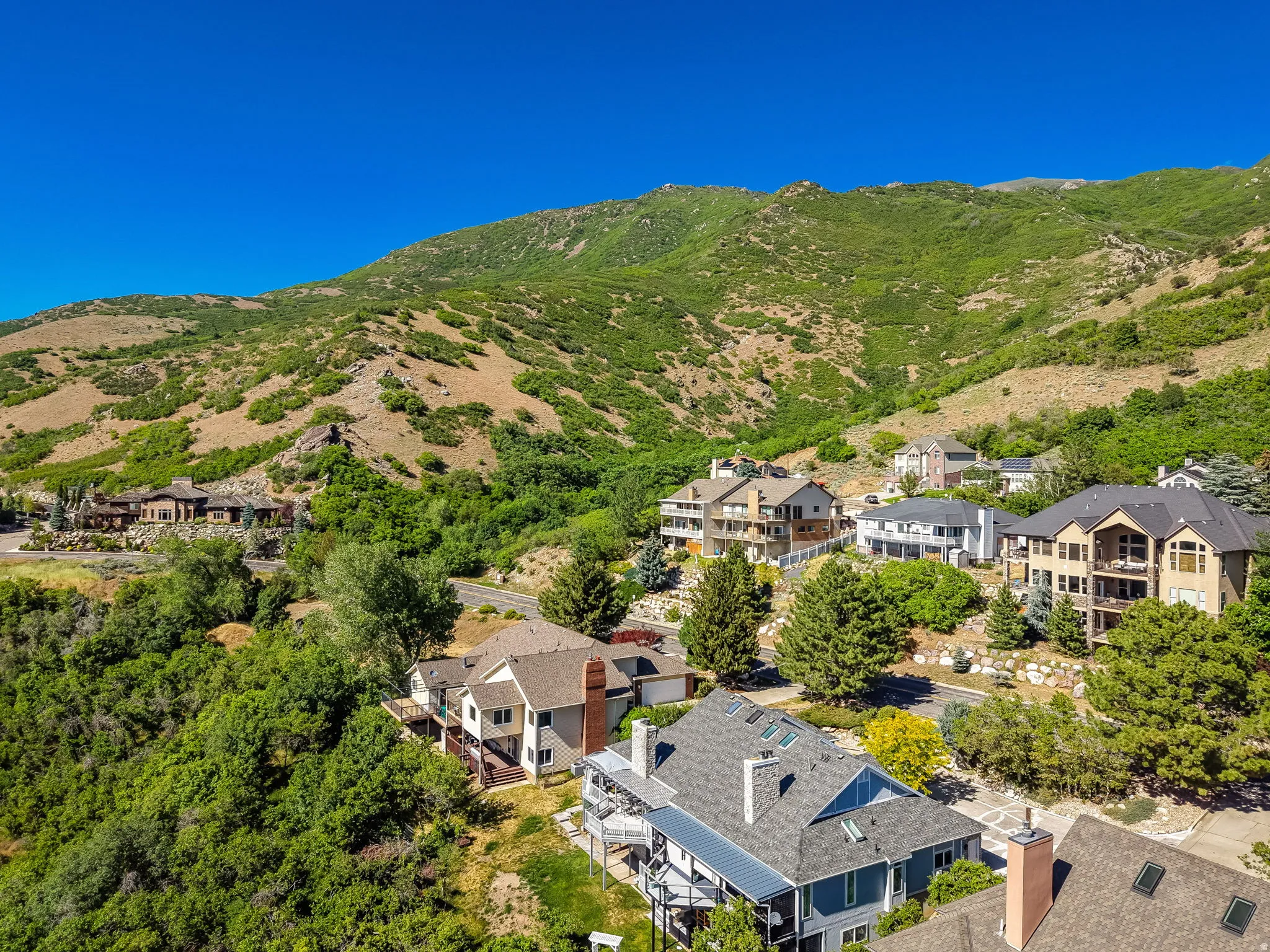 Mountainous terrain surrounds a residential area with several multi-story homes