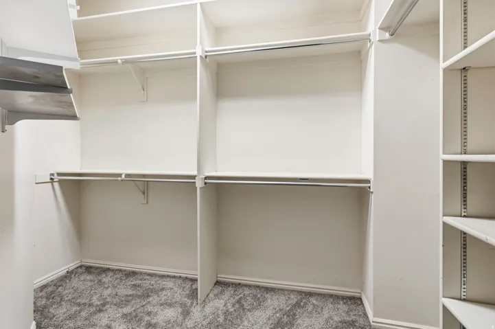 Built-in shelving and hanging rods, adjustable shelving system, wood-finish shelving, and carpeted flooring