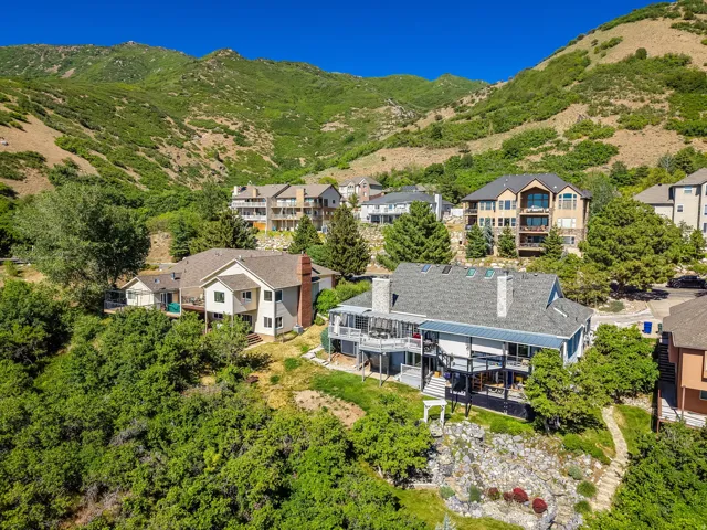 Expansive hillside property featuring a multi-level residence with multiple decks, a stone chimney, and a grey shingle roof