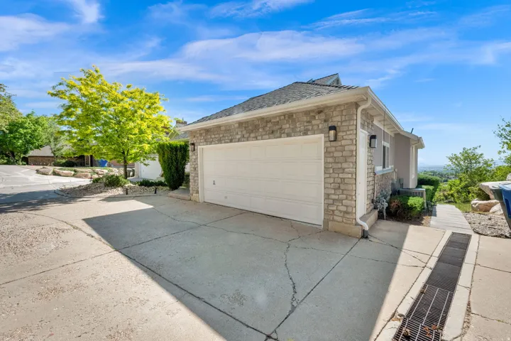 Attached garage with a white panel door, stone veneer facade, dual exterior sconces, and a concrete driveway