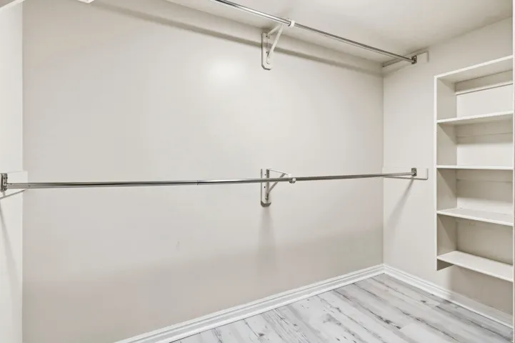 Chrome hanging rods, built-in shelving, and wood-finish flooring
