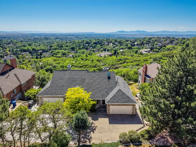 Expansive property featuring a multi-car garage, mature landscaping, and a broad cityscape stretching to distant mountains