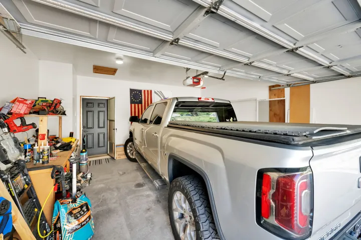 Spacious garage featuring a concrete floor, bright white walls, and two overhead garage doors